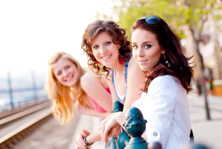 Three women posing for a picture on the side of a bridge.