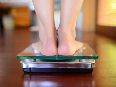 A person standing on a scale with their feet on the floor.