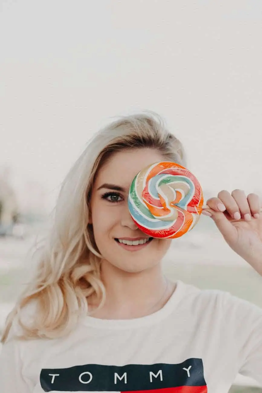 A woman holding a lollipop in front of her face.