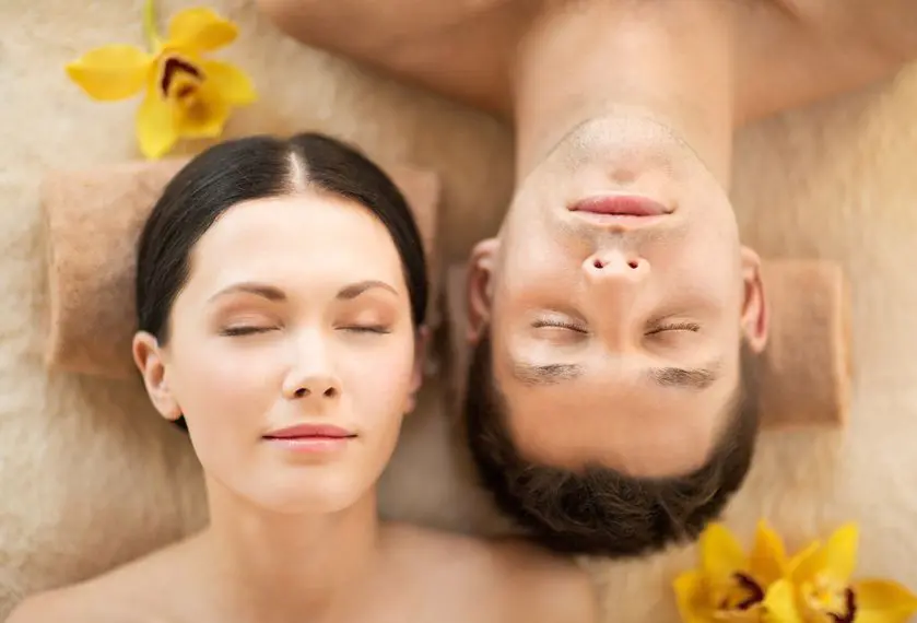 A man and woman laying on the ground with flowers.