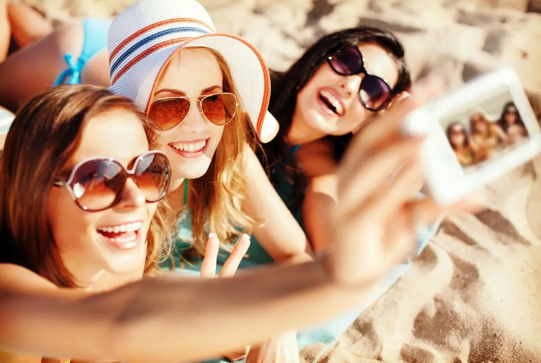 Three women taking a picture of themselves on the beach.
