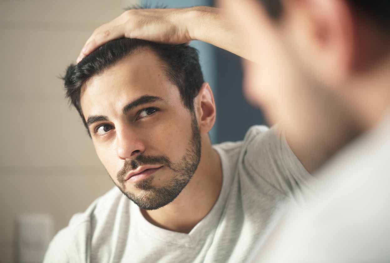 A man looking at his hair in the mirror