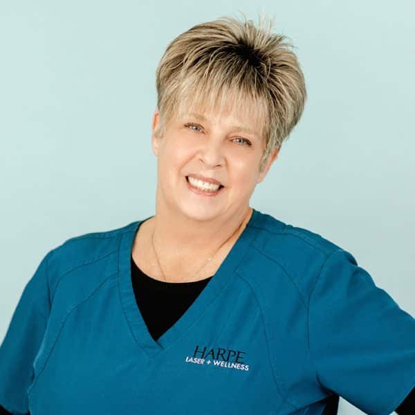 A woman in blue scrubs smiling for the camera.