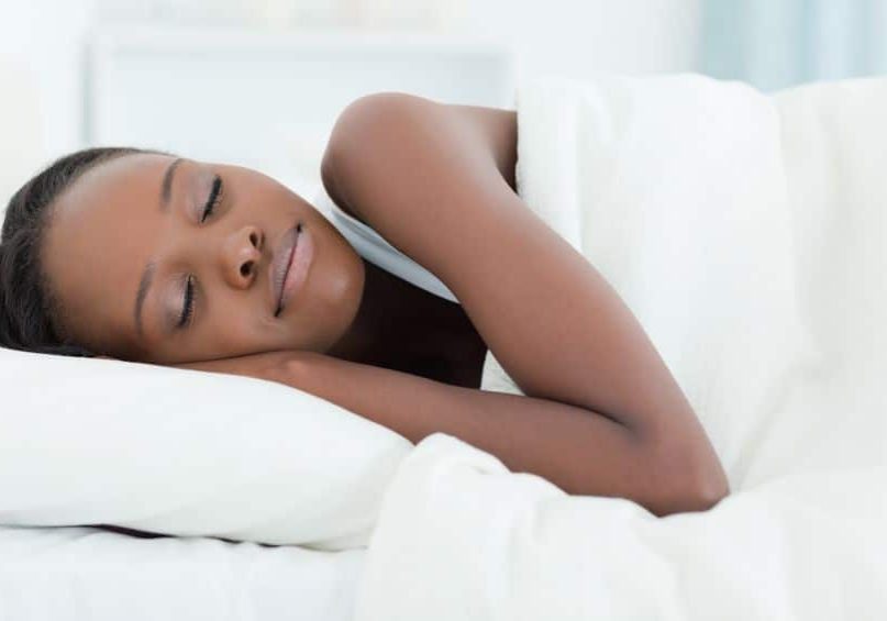 A woman sleeping in bed with her head on pillows.