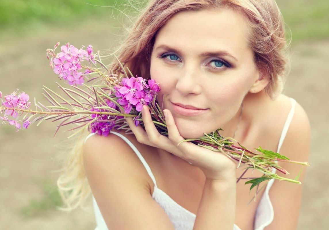 A woman holding flowers in her hands and smiling.