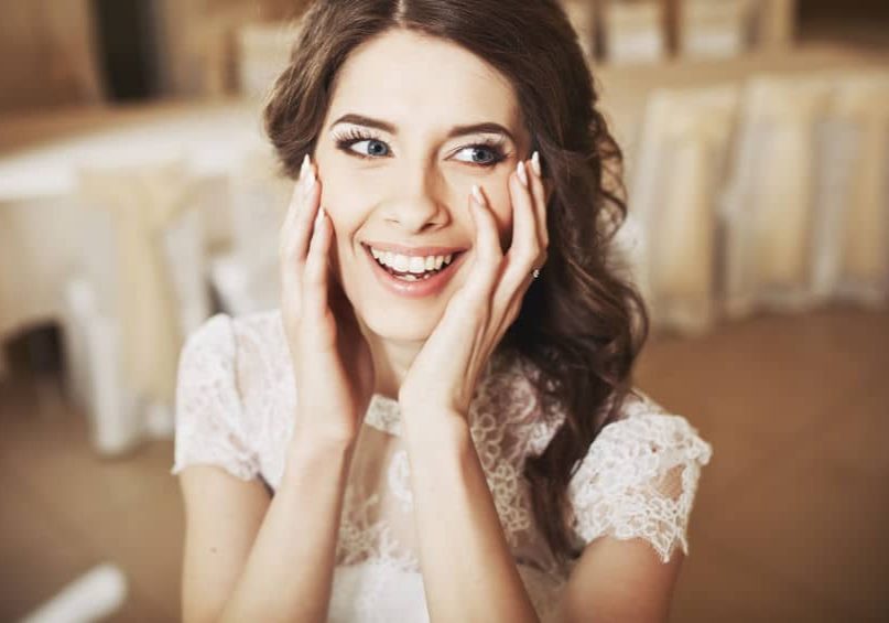 A woman smiling with her hands on her face.