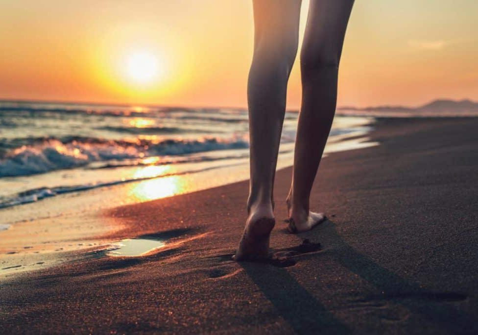 A person standing on the beach at sunset.